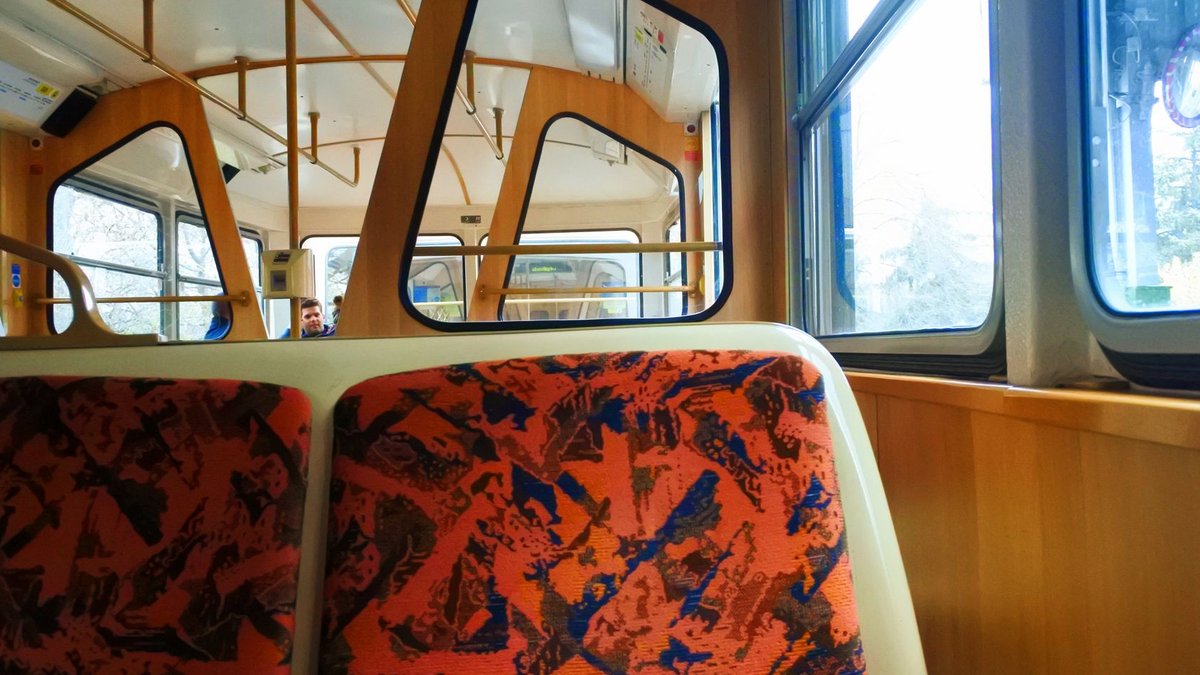 View of a modern train interior featuring patterned seats and large windows.