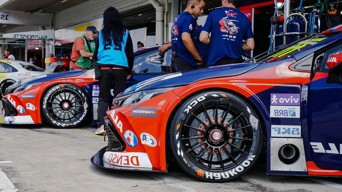Australia’s vintage racing cars face tobacco livery ban Close-up of colorful race cars in a pit stop with mechanics and crew preparing for a motorsport event.