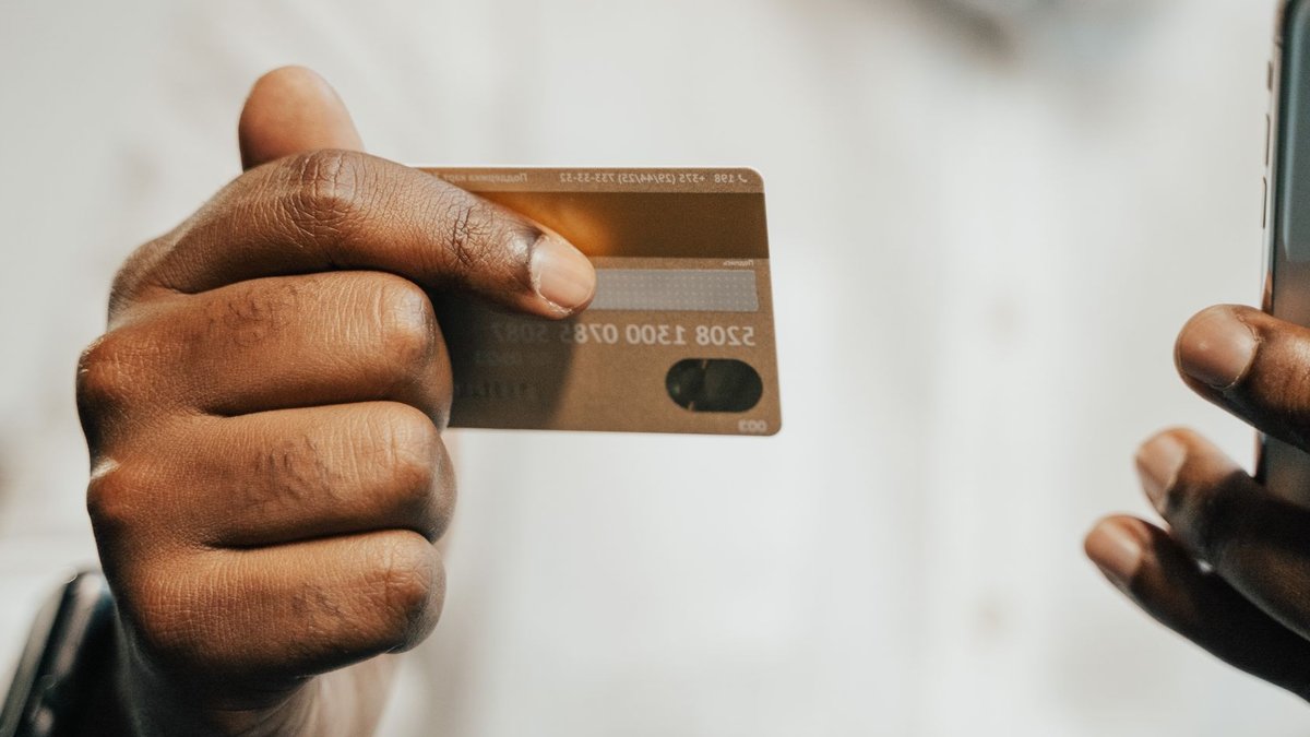 Fiserv overhauls banking tech amid stability concerns Person using a smartphone and credit card for online shopping or payment.