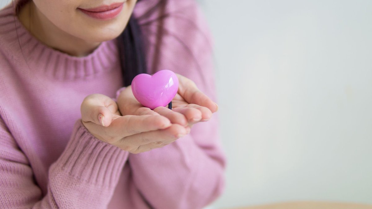PHA launches Sulu Subchapter to expand heart care access A woman in a pink sweater holding a pink heart-shaped toy, symbolizing love and kindness.