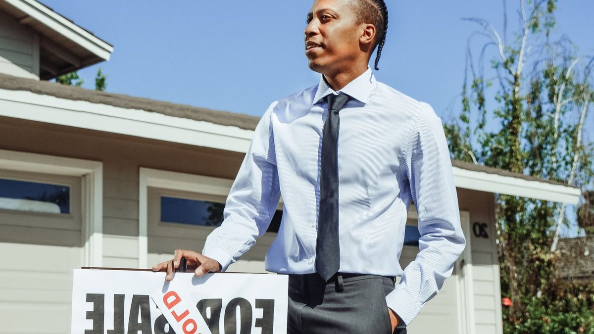 Real estate agent presenting a sold sign in front of a residential property.
