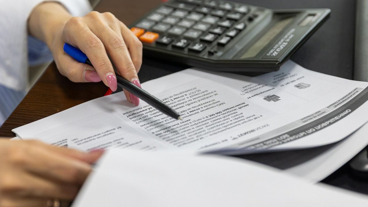 British workers neglect pensions despite valuing them Close-up of a woman's hand reviewing financial documents with a calculator.