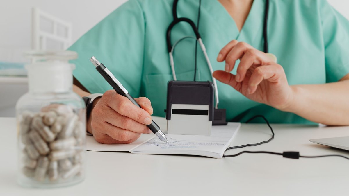 A medical professional writing a prescription in a clinical setting.