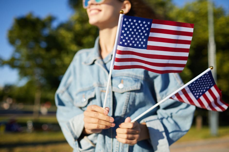 Mulher segurando duas bandeiras dos Estados Unidos