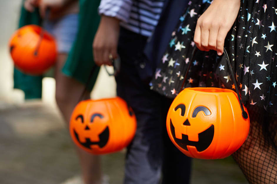 Crianças segurando balde de abóbora do halloween