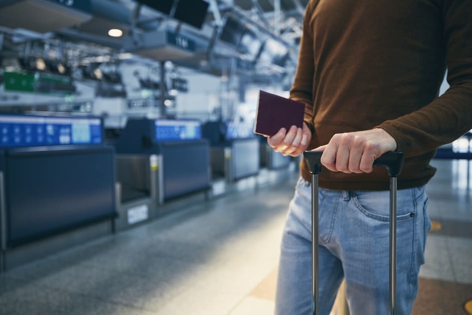 homem com mala de viagem e passaporte esperando para fazer check in no aeroporto