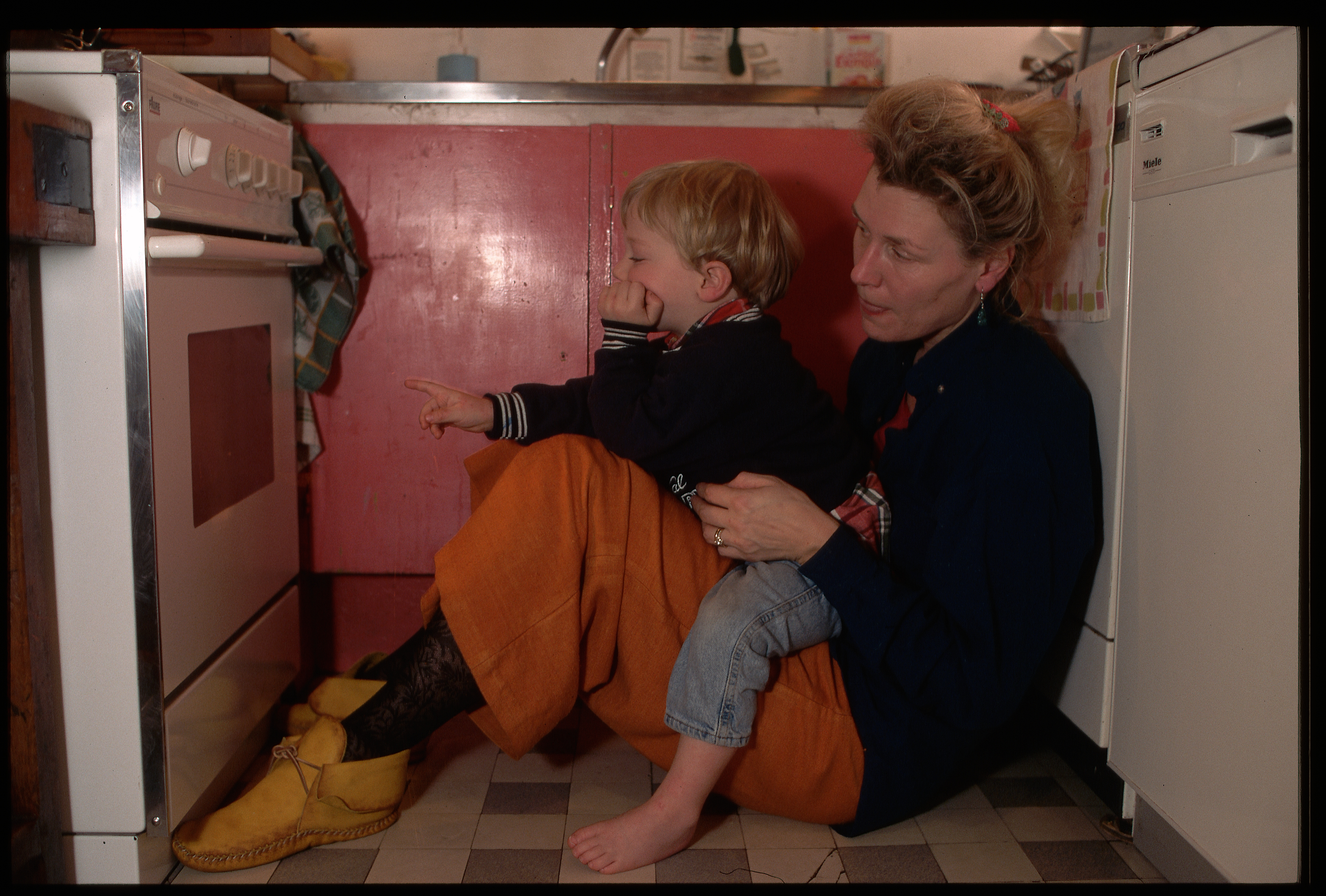 Mother and child sitting on floor by oven - Getty Images