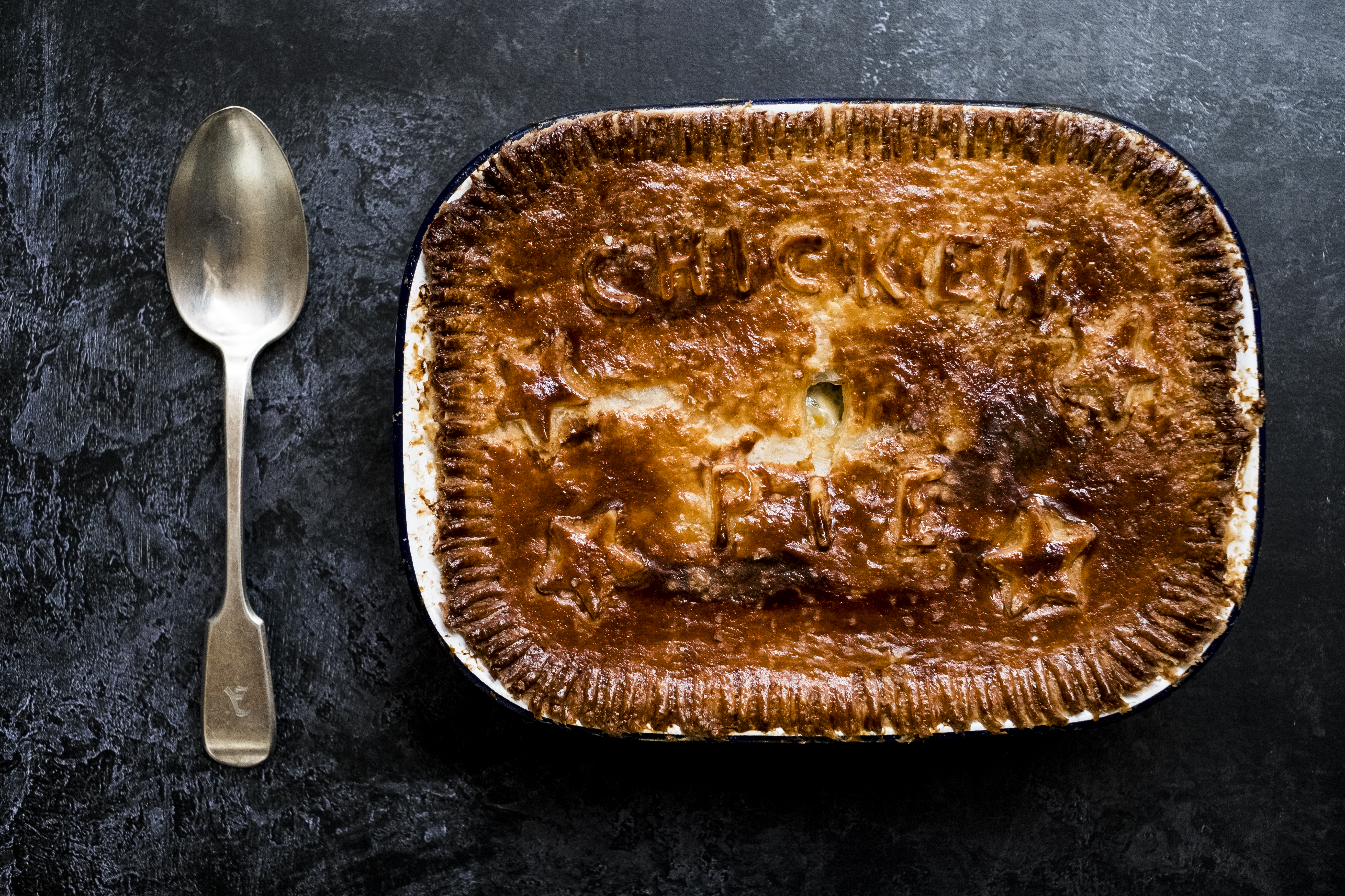 A photo of a chicken pie with a puff pastry crust. The words 'chicken pie' are faintly legible in the crust.