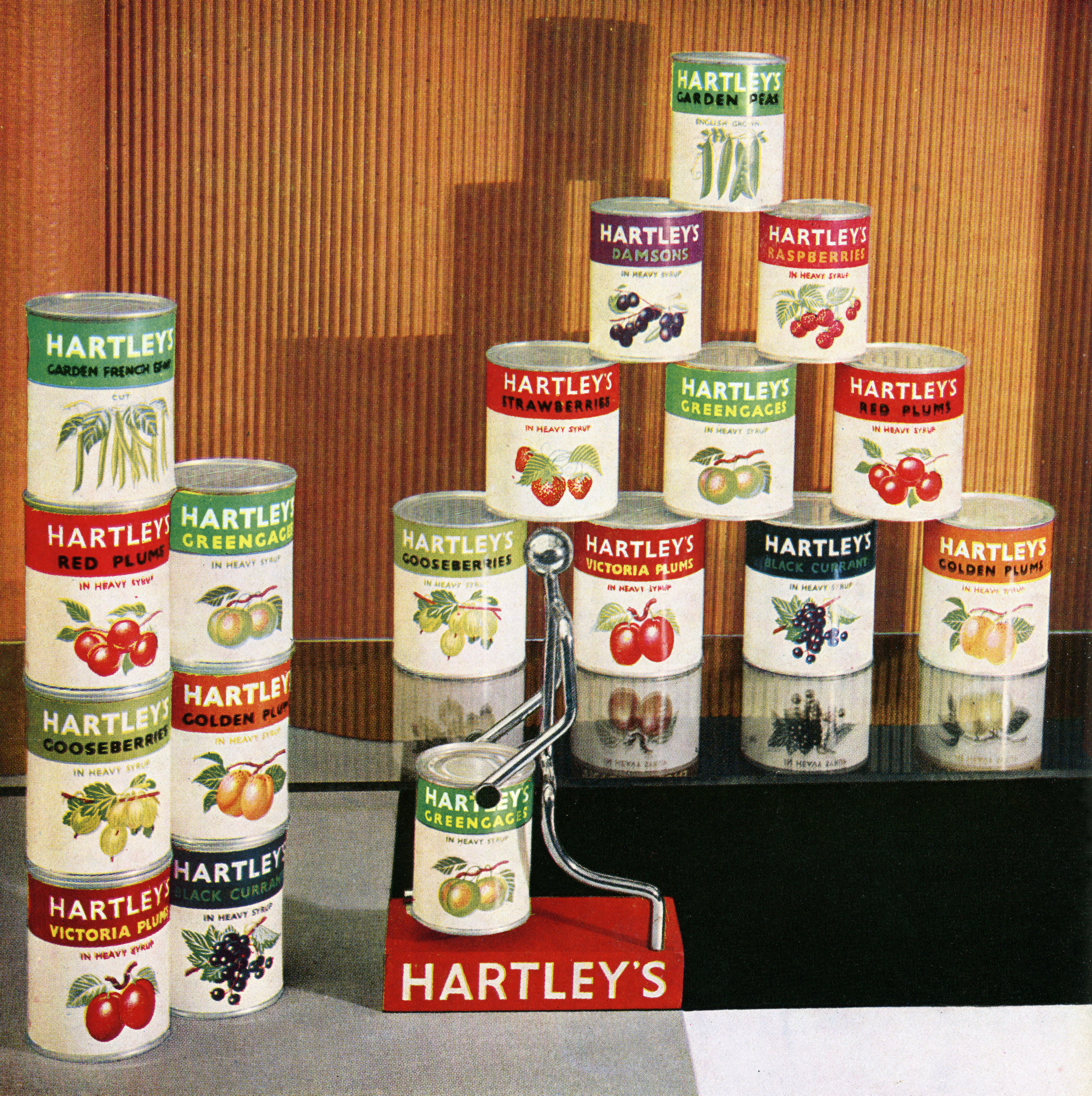 Display of vintage canned vegetables and fruits stacked in a store; screen print from a photograph, 1940s.
