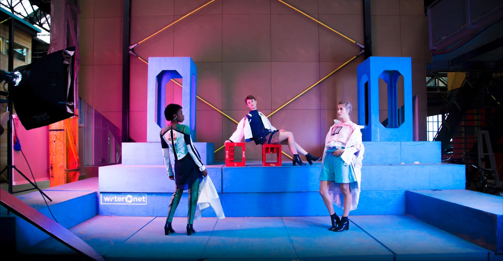 Three fashion models on futuristic neon-lit stage set