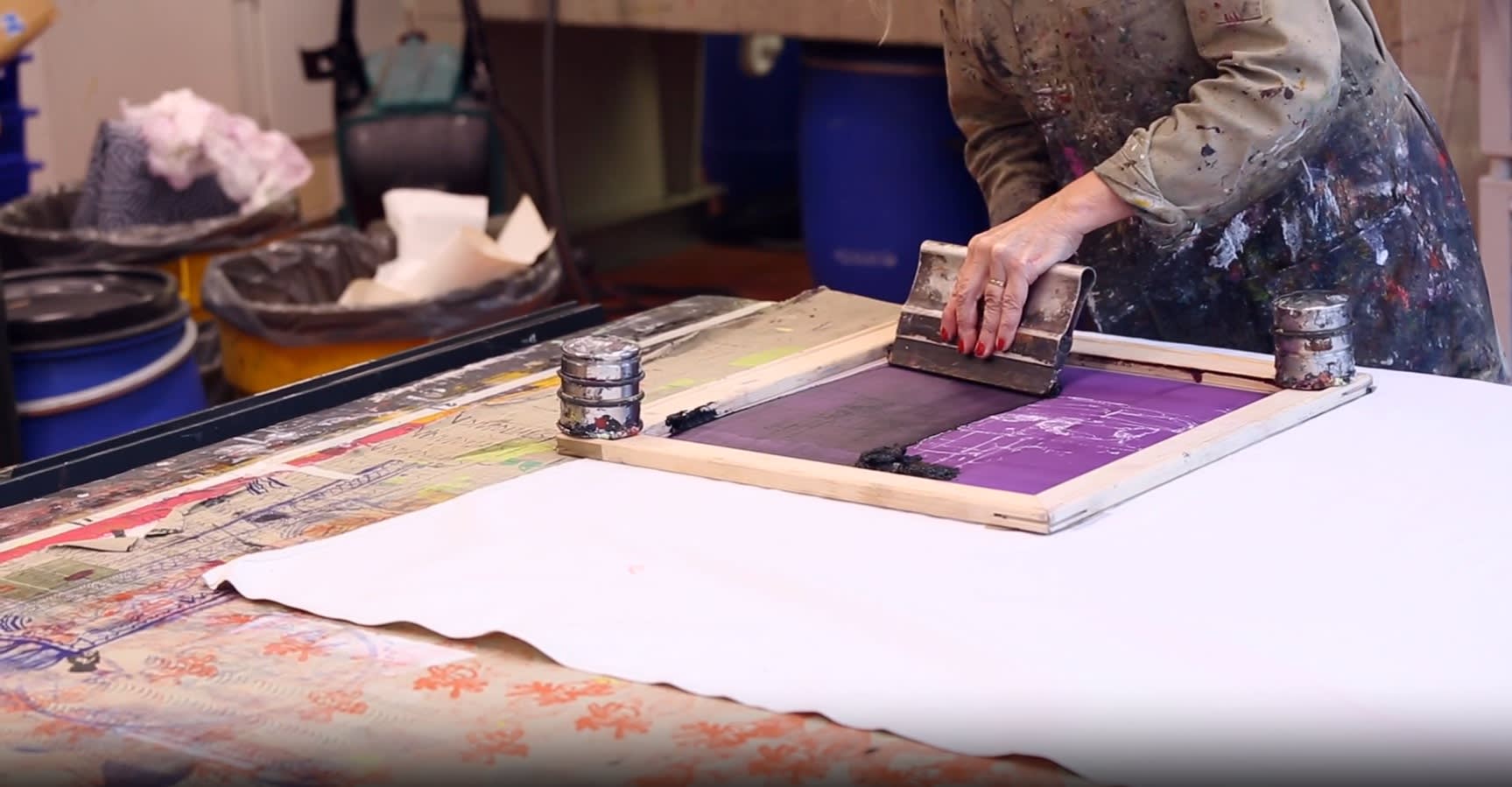 Person screen-printing fabric on large worktable