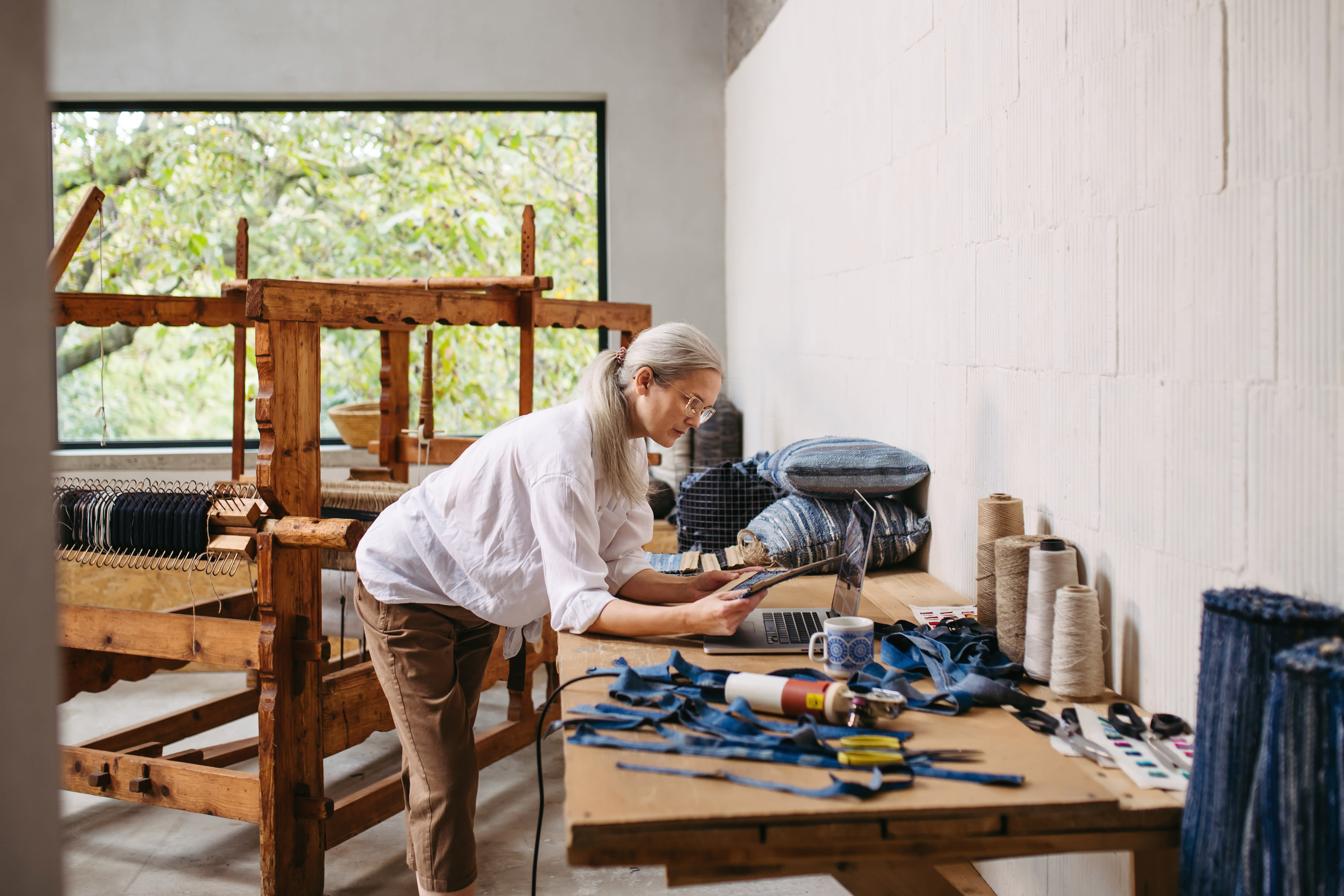 Person working in textile studio with loom and fabric materials