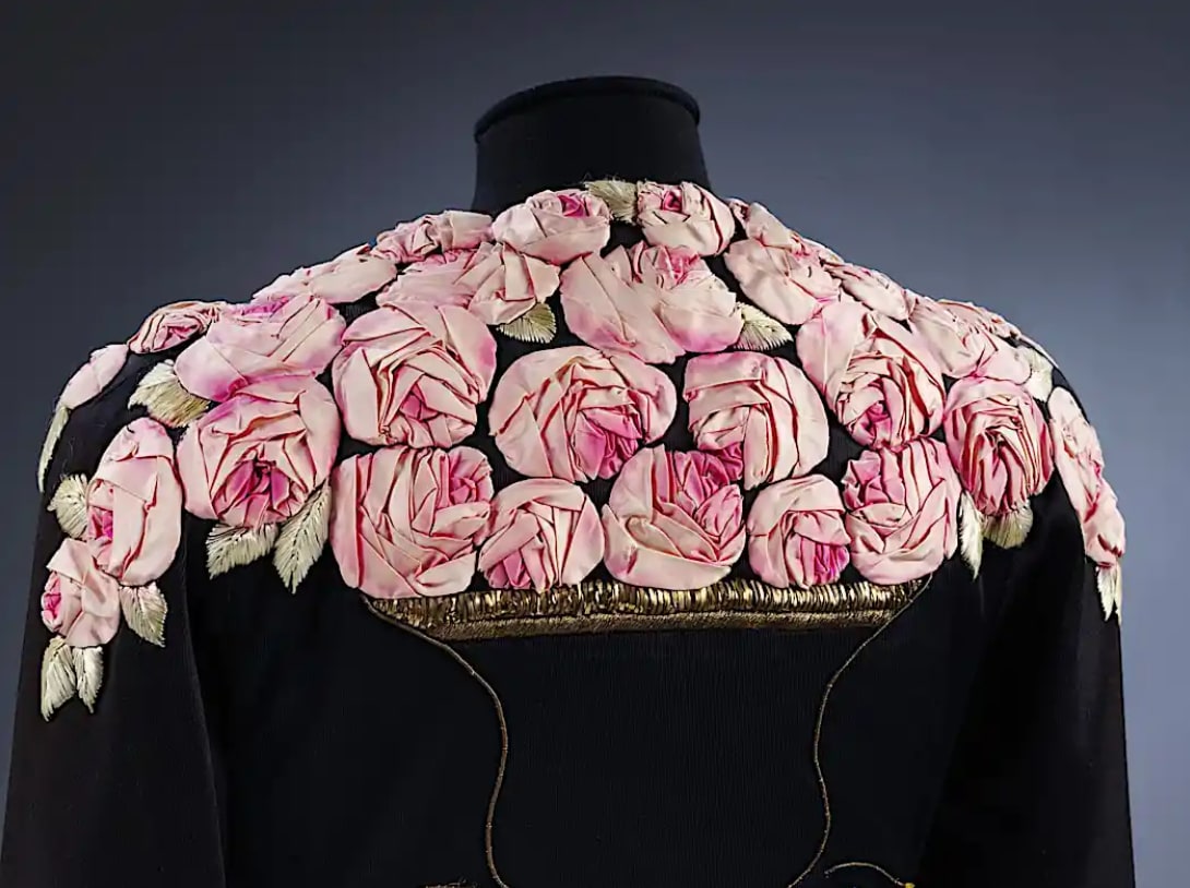 Black garment with pink fabric roses embroidered across shoulder