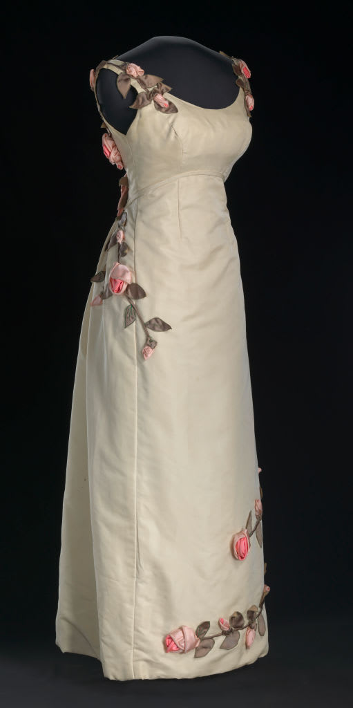 An ivory dress decorated with swirls of handmade fabric rose vines