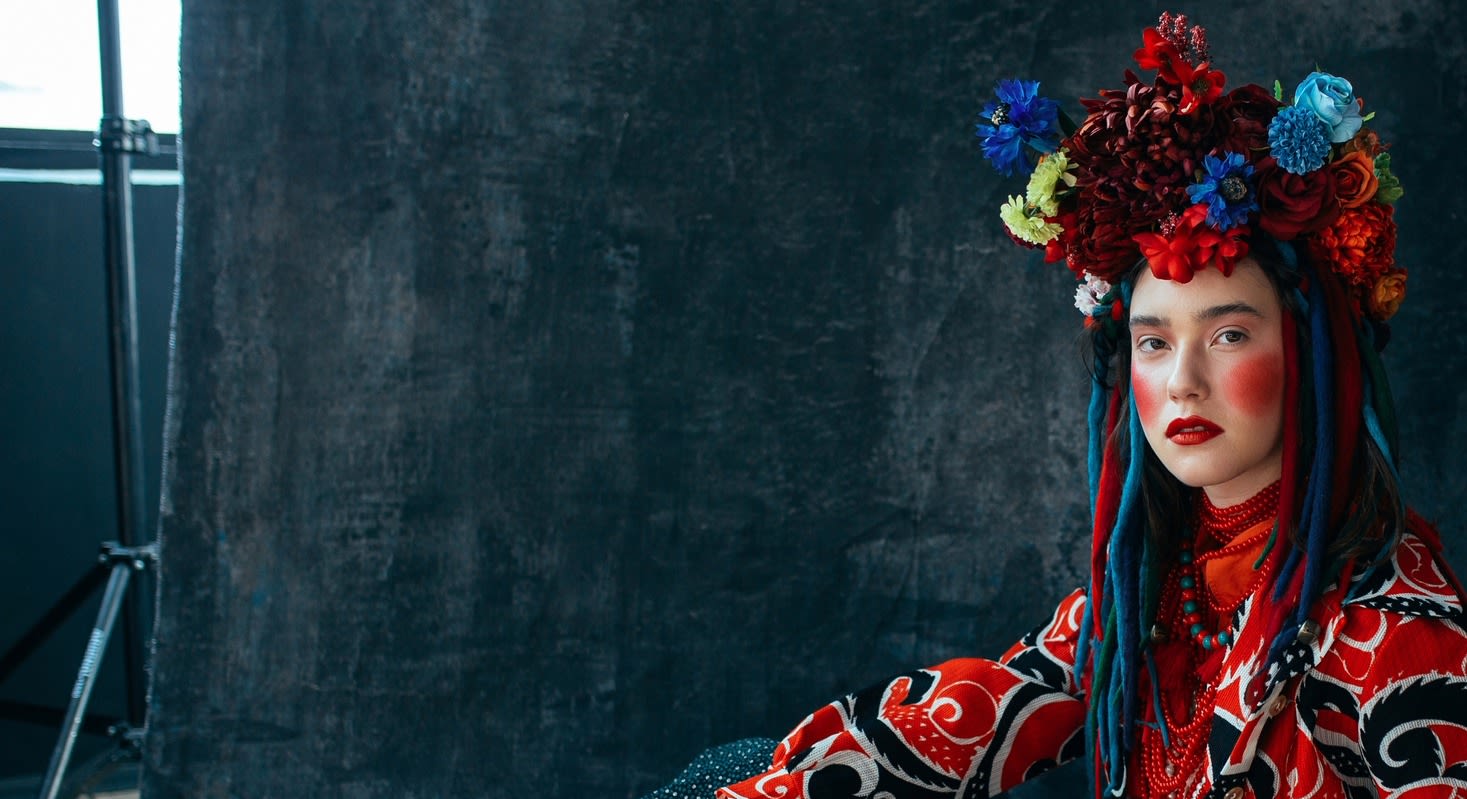 A person in vibrant traditional clothing with a floral headdress