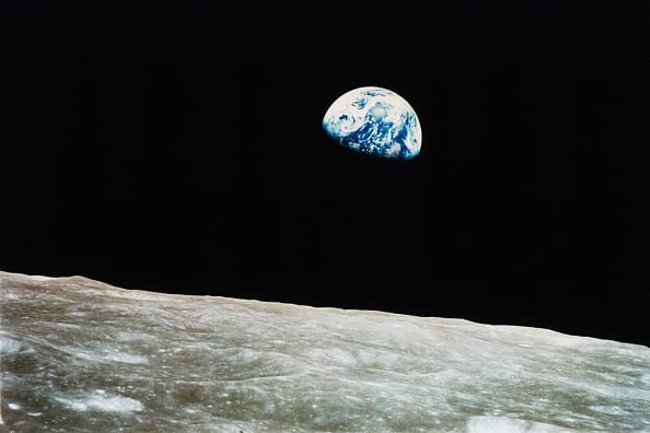 Earth rising above the Moon's horizon against black space