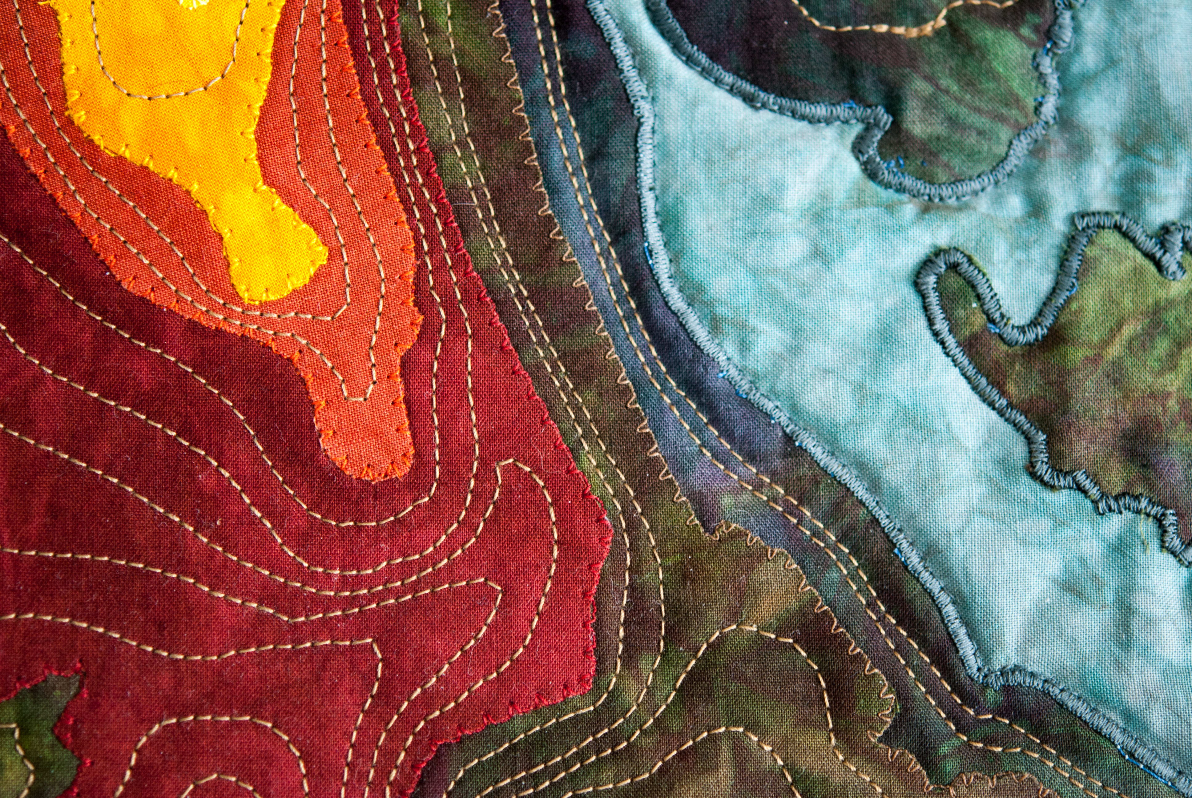 Colorful quilt resembling topographic map with stitched contour lines