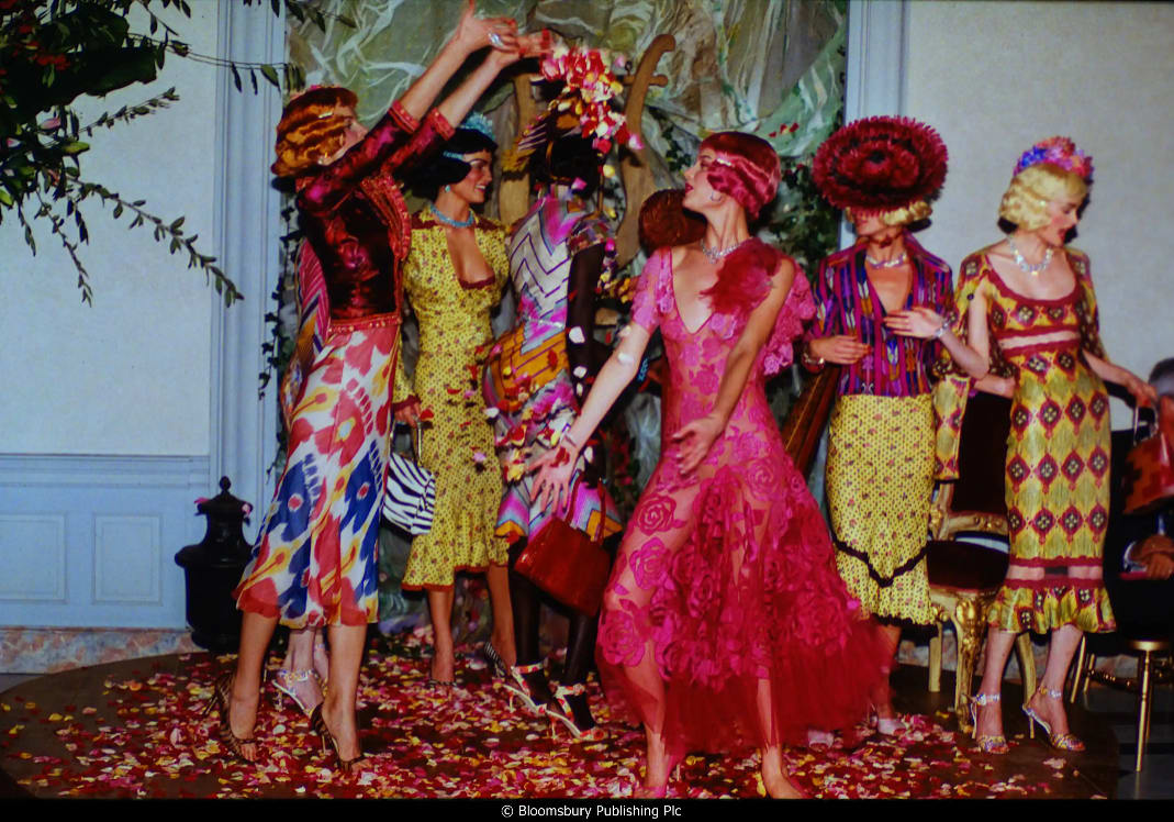 Models in vibrant outfits dancing amid scattered flower petals