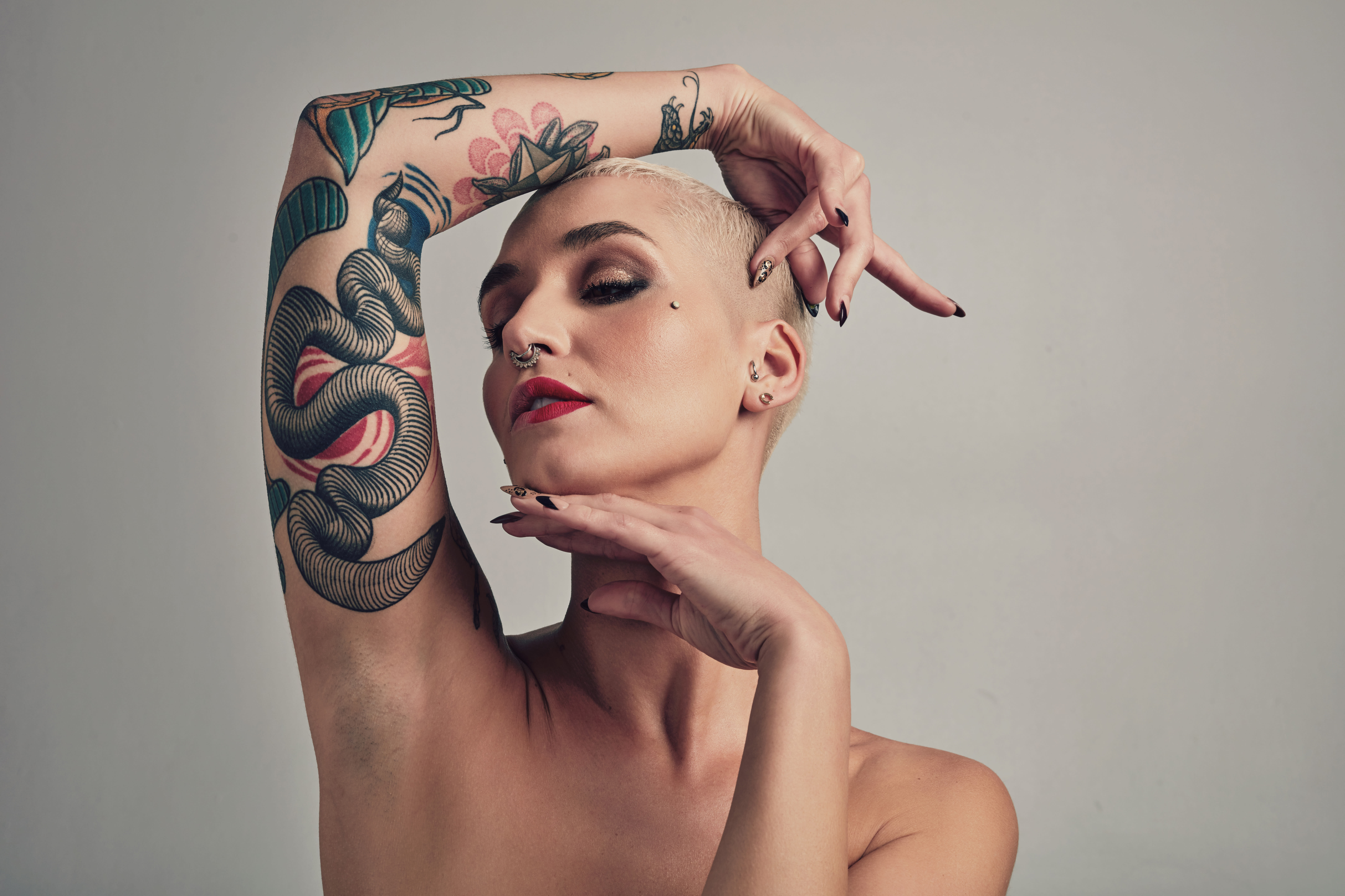 Portrait of tattooed and pierced woman in grey background