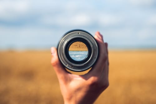 Looking through a camera lens at a golden wheat field on a sunny autumn day.