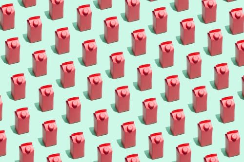 High angle view of many red milk or juice boxes on green background