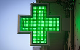 Lit up green cross sign attached to a wall