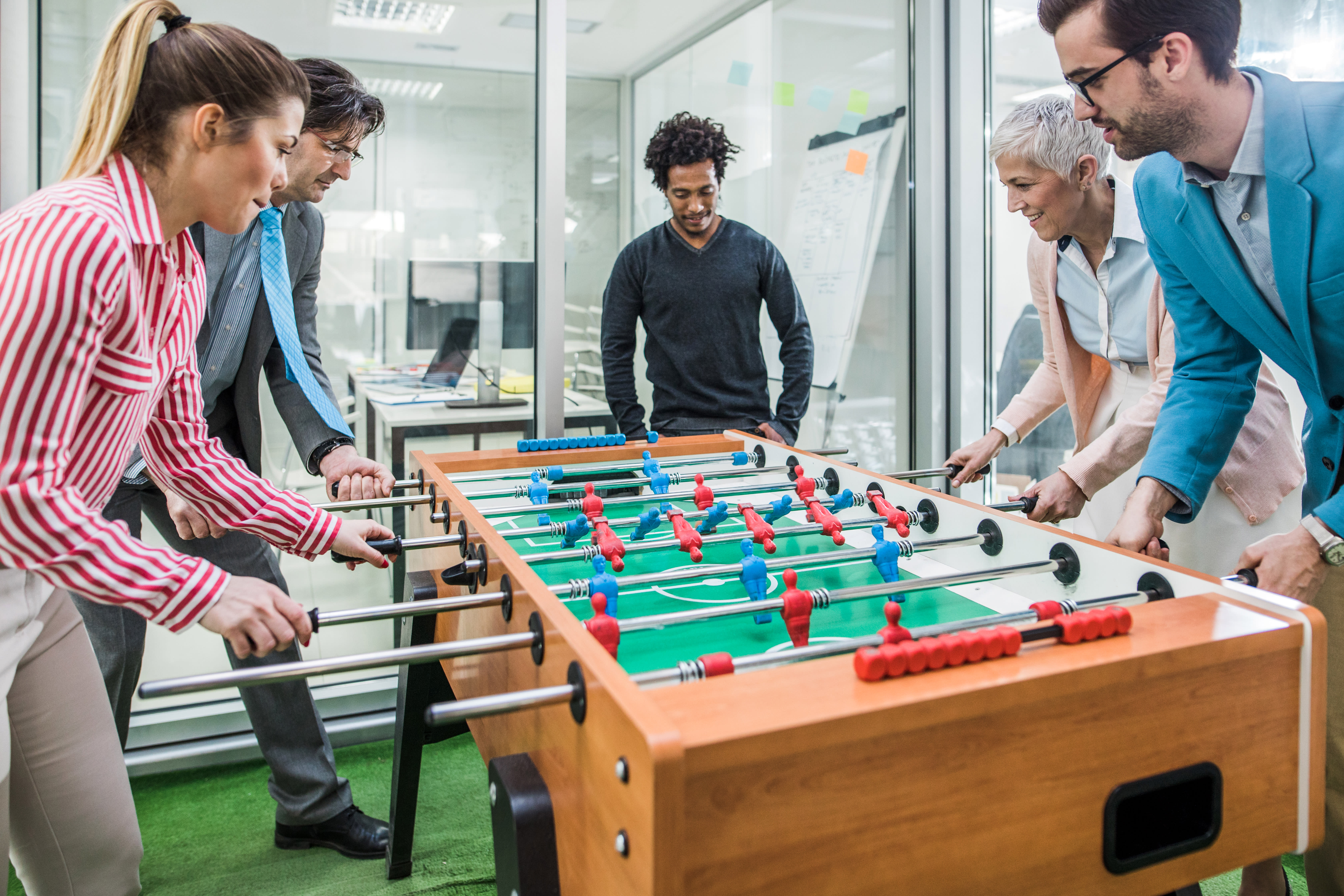 Team of happy entrepreneurs having fun on a break while playing table soccer.