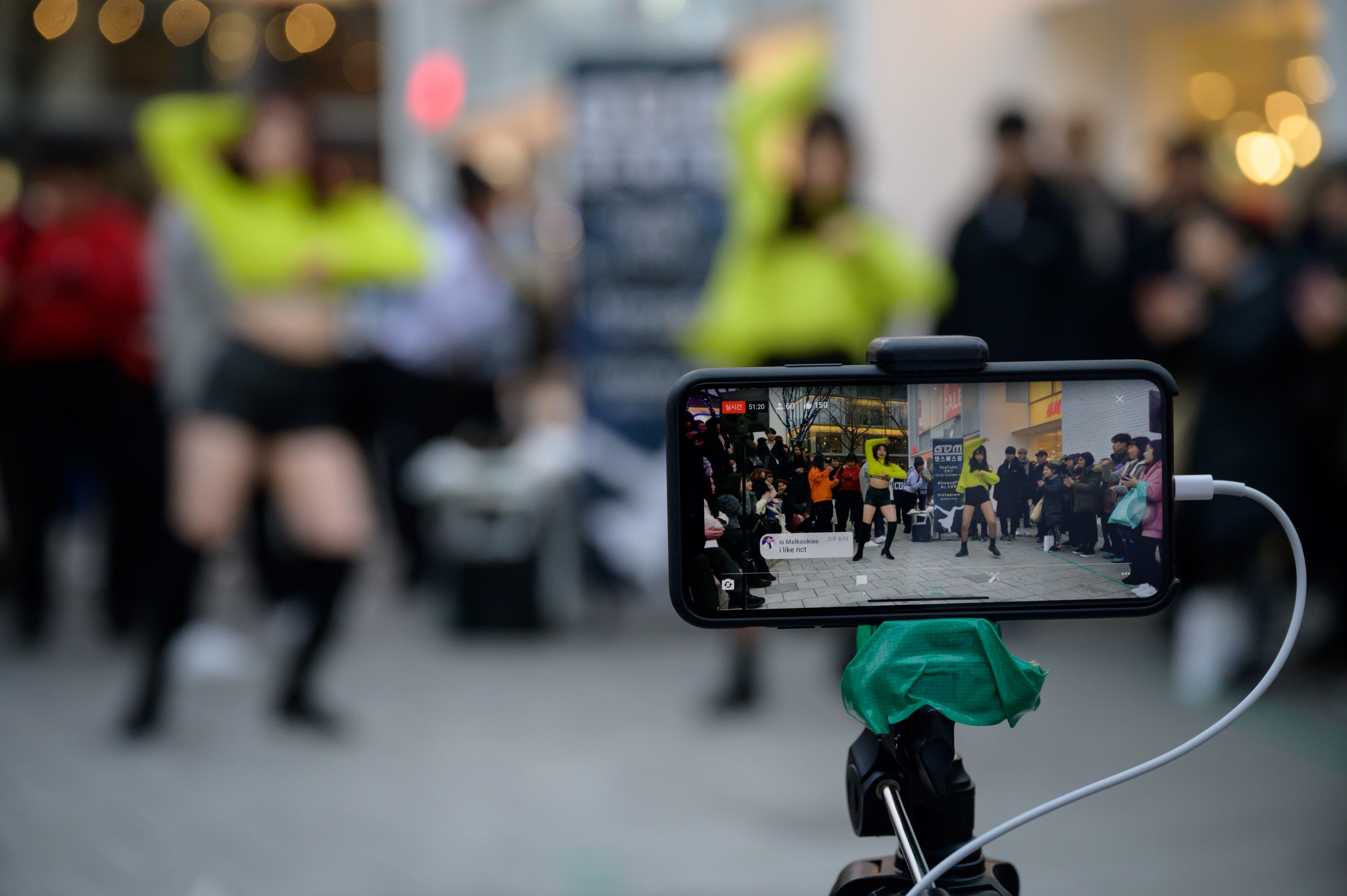 This photo taken on January 5, 2020 shows a smartphone recording footage of an amateur K-pop group performing on a street in the Hongdae district of Seoul. 
