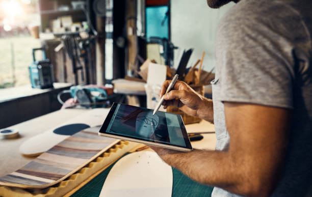 Shot of a man designing a skateboard on his tablet in the workshop