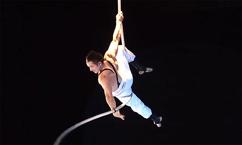 Aerial artist from Circus Oz hangs on to a rope
