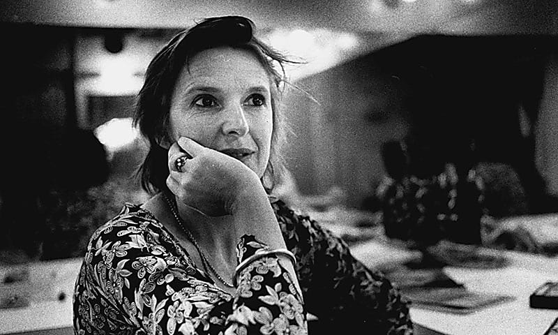 A black and white photo of a woman sat down resting her face on her hand
