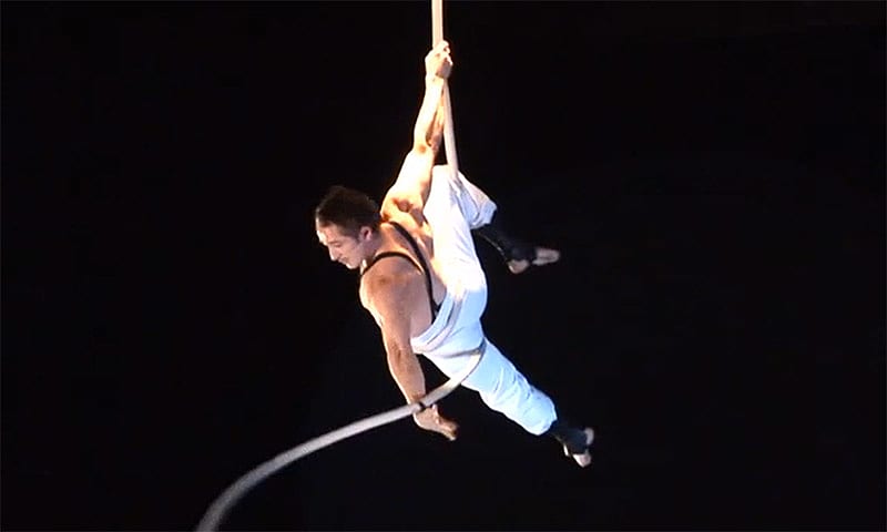 Aerial artist from Circus Oz hangs on to a rope