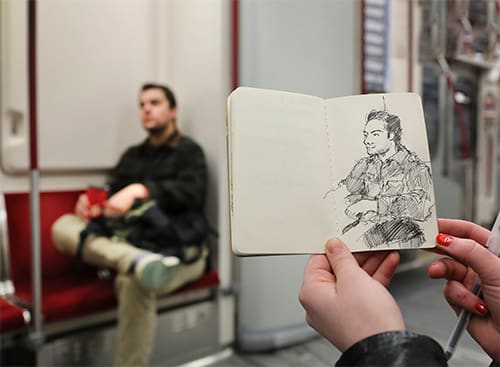 Someone sketches a person on the subway