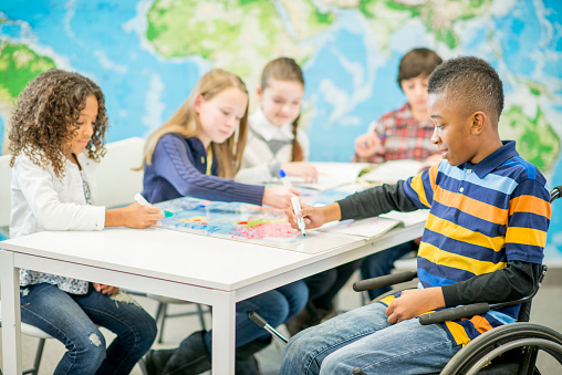 Primary Education - Children seated at a table working on art activities in a classroom.