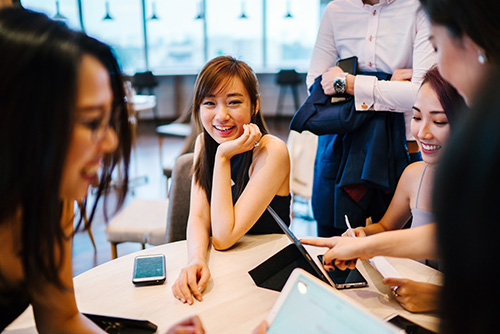 Youth - People sitting around a table collaborating in a shared workspace.