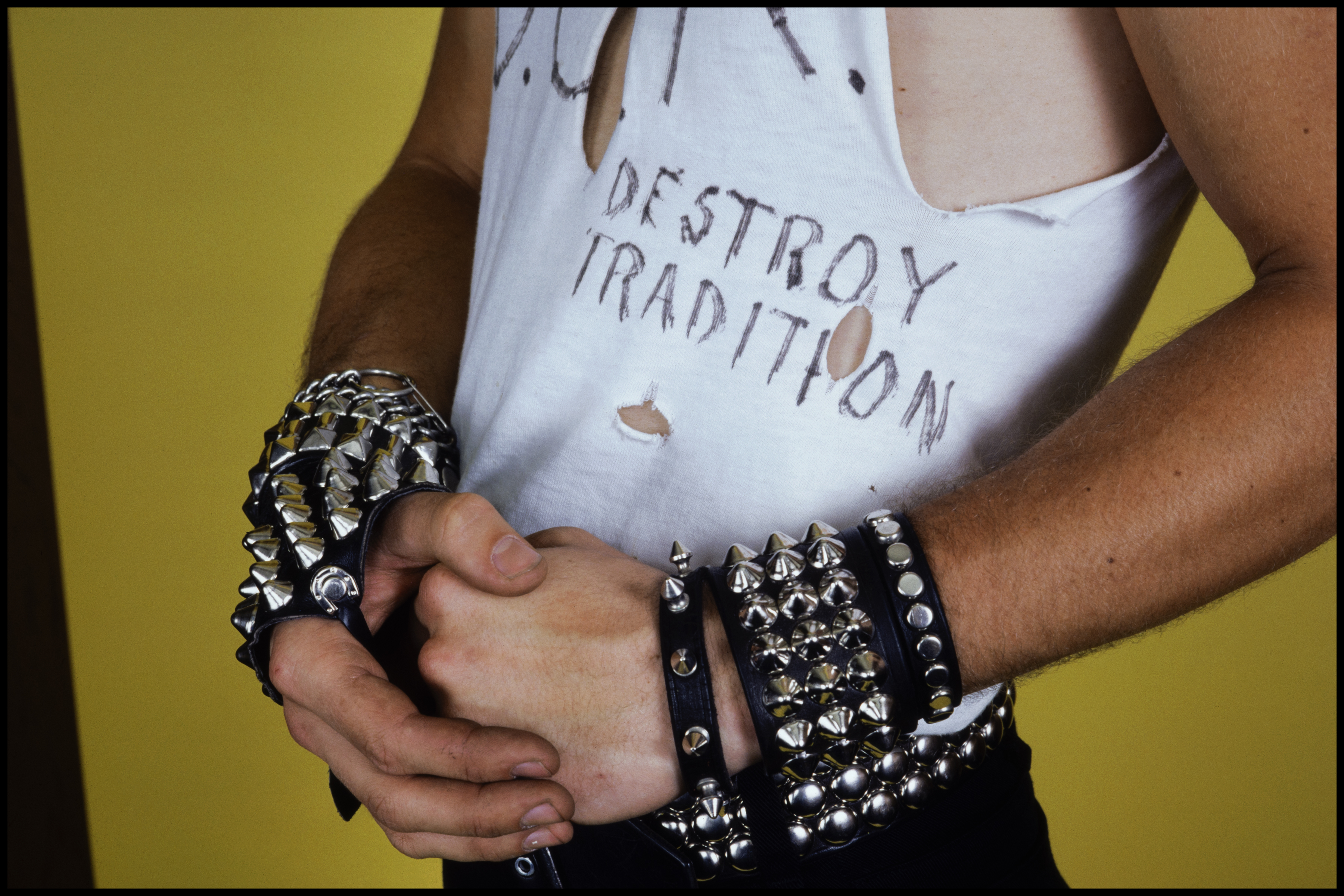 Student with studded wristbands and a torn t-shirt that features the text 'Destroy Tradition' in magic marker.