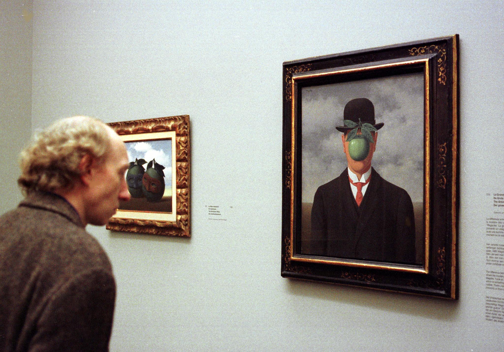 A man looks at the surrealistic painting The Great War during the Rene Magritte exhibition at the Brussels' Modern Art Museum