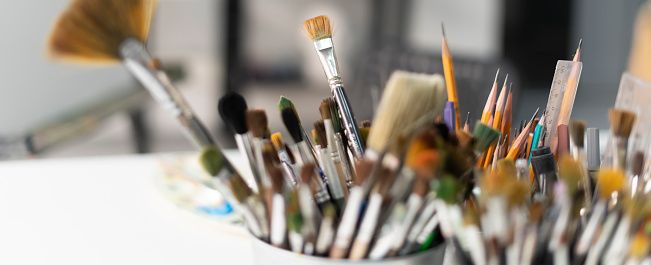 Pots of artists' pencils and paintbrushes
