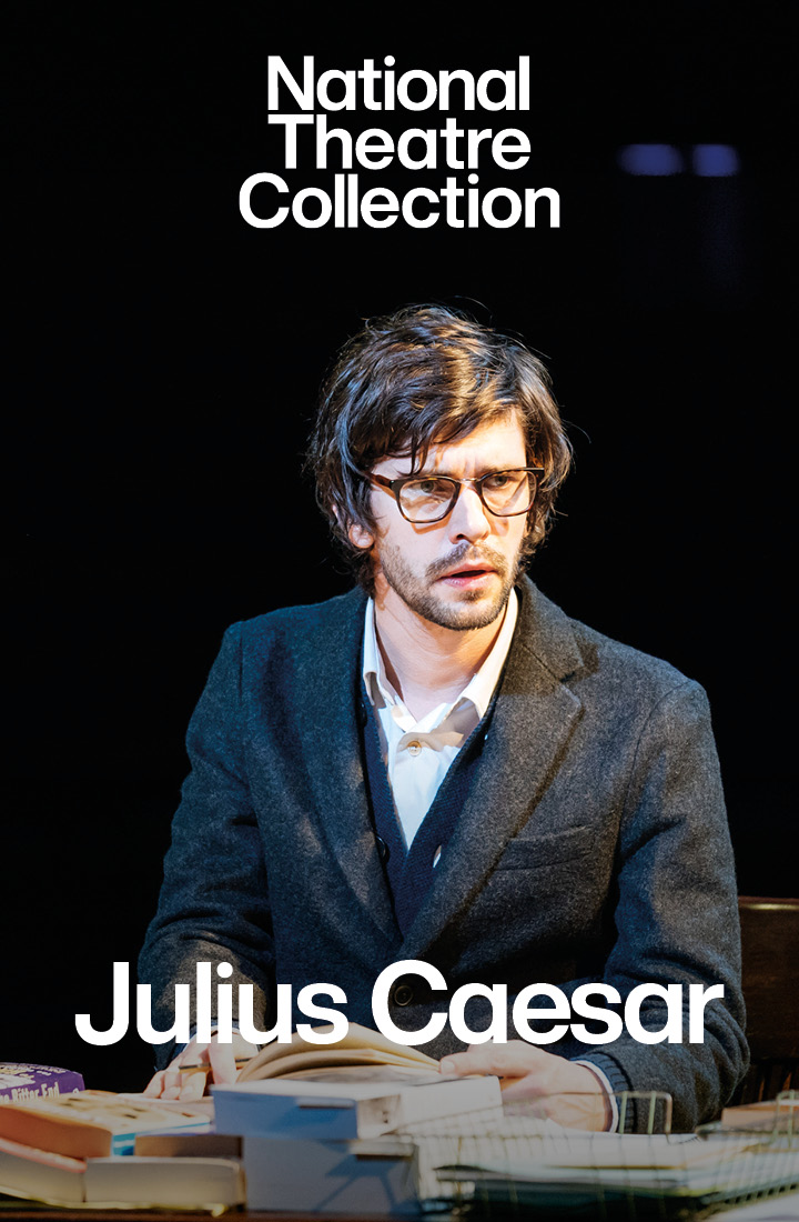 Actor David Calder sat on a chat looking stunned as a gun is being pointed towards him. He stars in the title role of Julius Caesar, a production recorded for the National Theatre