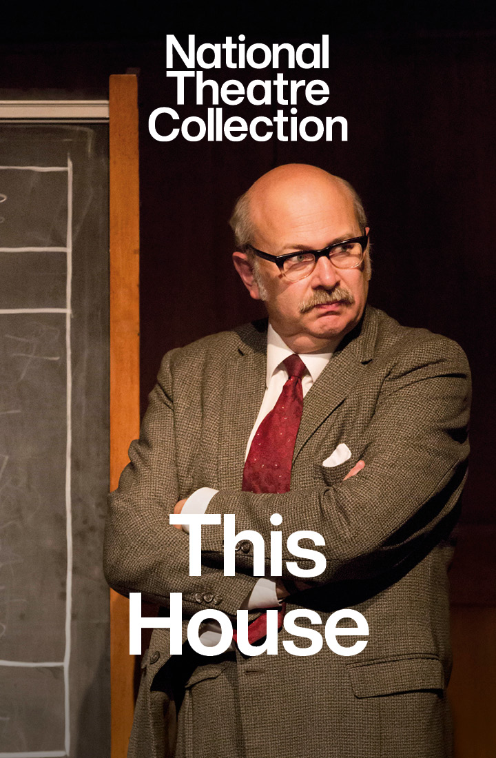 A member of Parliament standing in-front of a blackboard with his arms crossed in the production This House, recorded for the National Theatre