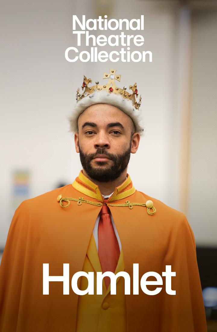 A man in a yellow suit wears an orange robe and a crown atop his head