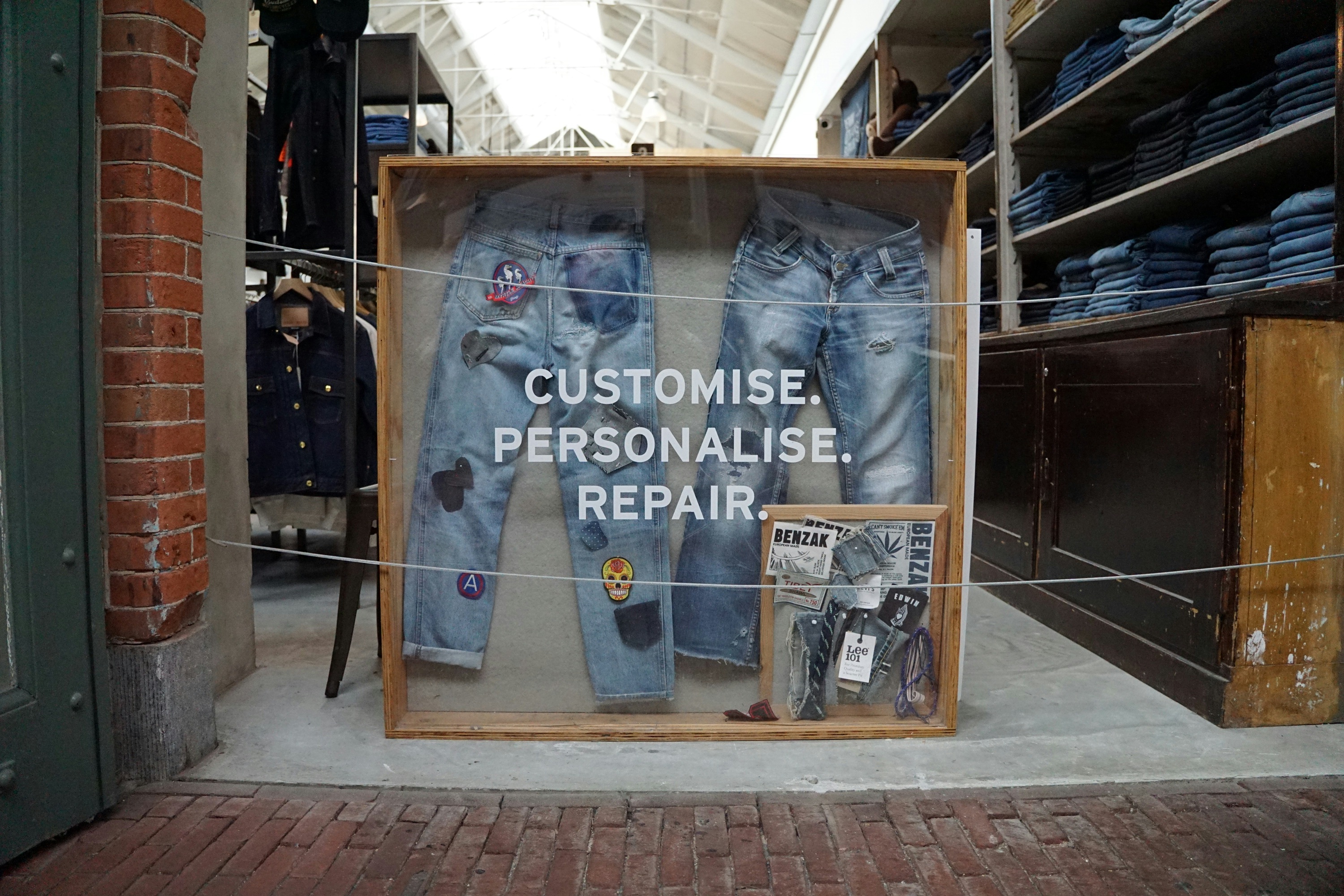 Display case showcasing customized and repaired denim jeans