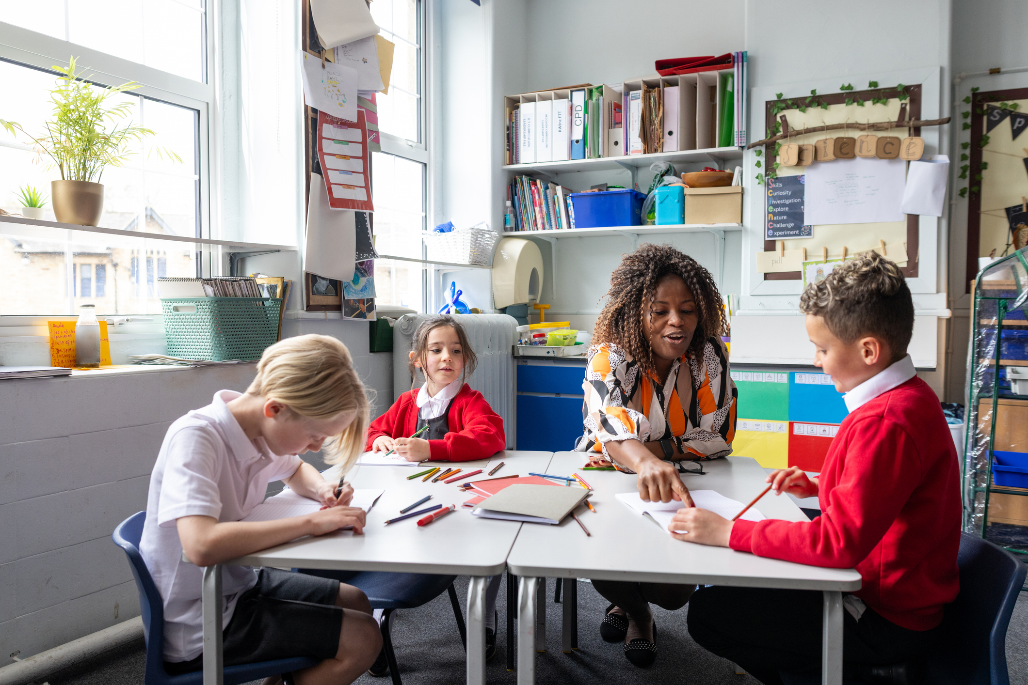 Photo of students and teacher sat at classroom desk 