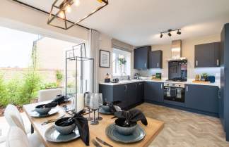 A dining table set for a meal sits in the foreground, with a modern kitchen featuring dark cabinets and stainless steel appliances in the background.
