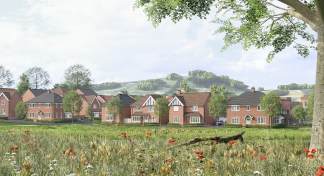 A field of wildflowers and tall grass stretches before a row of red-brick houses nestled against rolling green hills.