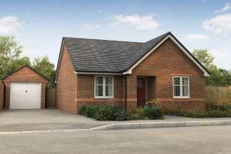 A brick bungalow with a detached garage sits on a paved driveway in front of a wooded area under a cloudy sky.