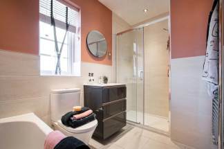 A modern bathroom with a vanity, mirror, and shower enclosure, set against a warm peach-colored wall.