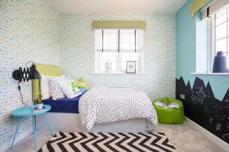 A cozy and vibrant children's bedroom with a patterned bedding set, colorful accents, and a chalkboard wall in the background.