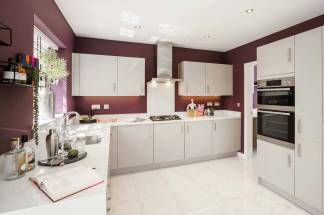 A modern, well-equipped kitchen with white cabinets, stainless steel appliances, and burgundy-colored walls, creating a stylish and functional space.