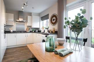 A modern, well-lit kitchen with white cabinets, wooden countertops, and a large window overlooking a potted plant and other decorative elements on the table.